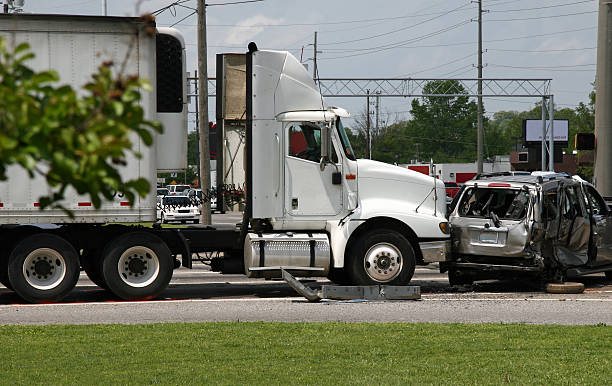 A tractor-trailer and a heavily damaged passenger vehicle after a collision at a highway intersection